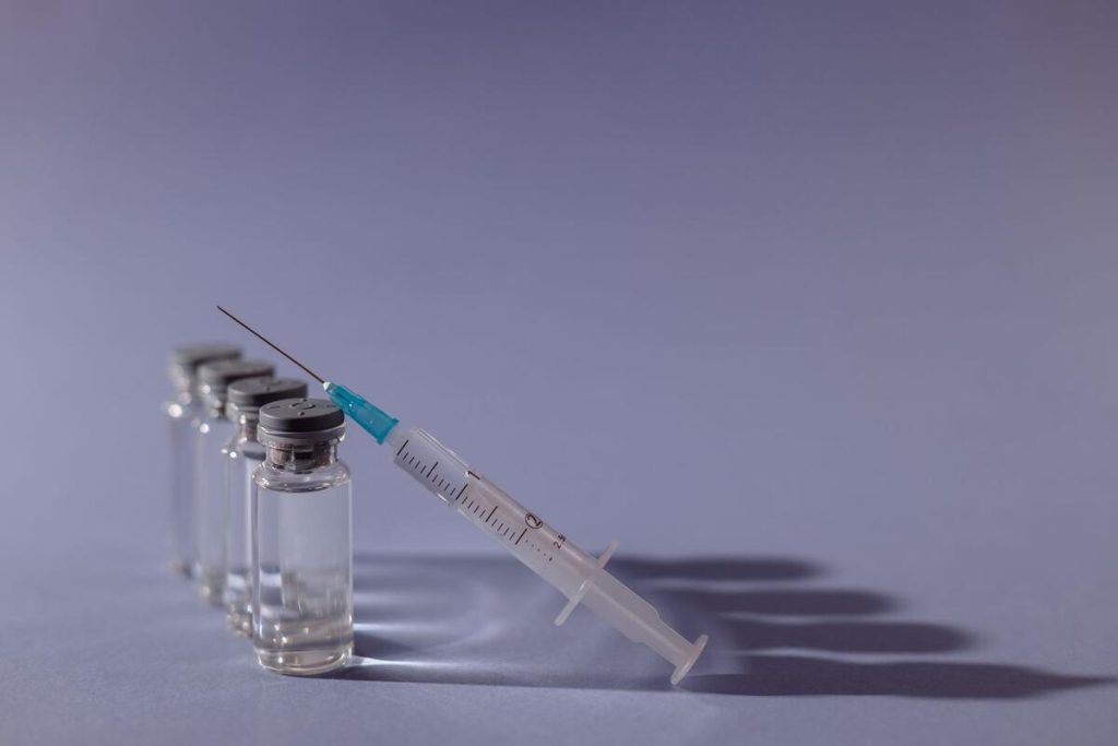 glass vaccine vials and syringe on white medical tray