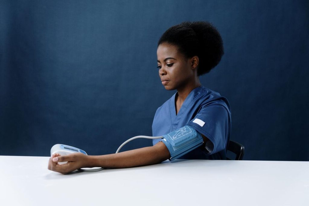 pregnant woman having blood pressure measured by healthcare professional in clinic, no visible faces