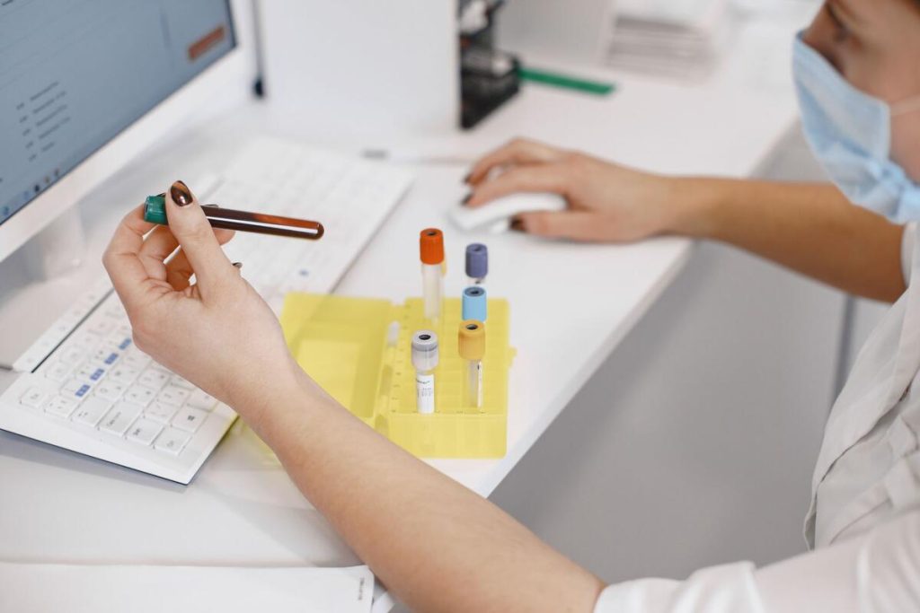laboratory technician analyzing blood sample under microscope, clinical lab, no faces
