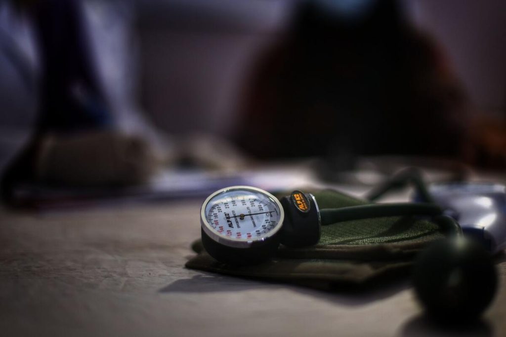 blood pressure monitor and stethoscope on wooden table, close up