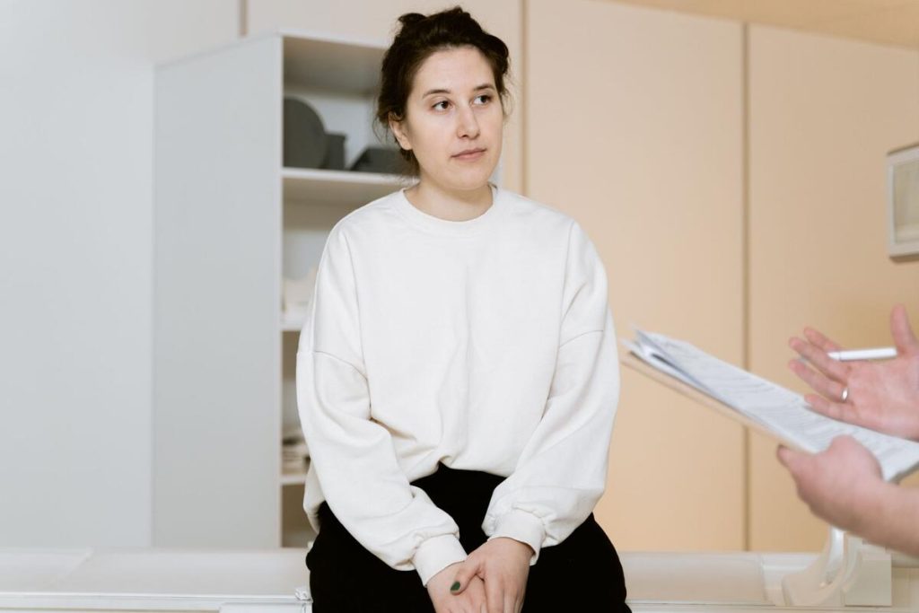 woman discussing symptoms with doctor in clinic office, serious conversation