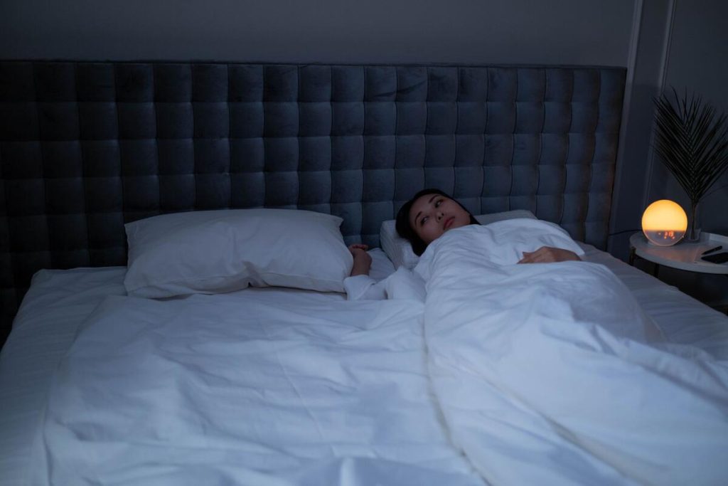 person lying awake in bed at night unable to sleep, insomnia