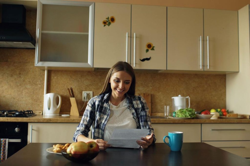 woman reading a letter at home kitchen table, no face visible