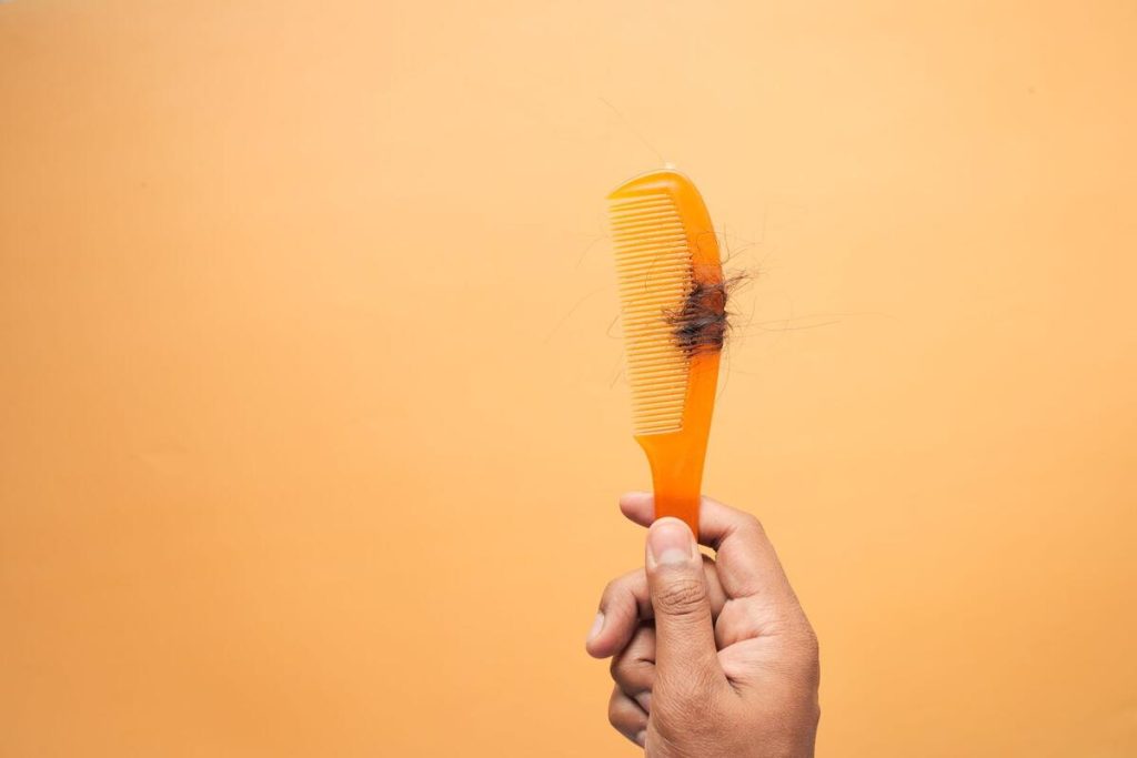 hairbrush with fallen hair strands on white bathroom counter, no people
