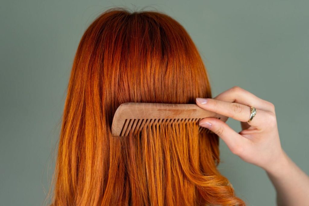 woman's hand holding hairbrush over sink, close up on hair strands, no face visible