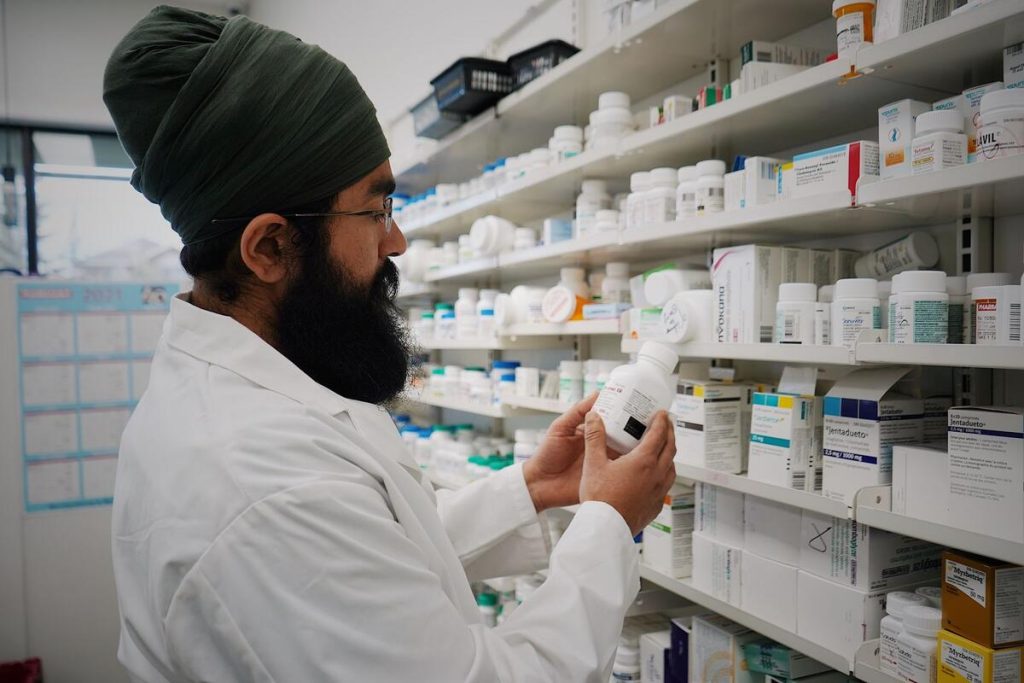 Pharmacist checking medicine boxes on shelves in a hospital pharmacy, no visible faces