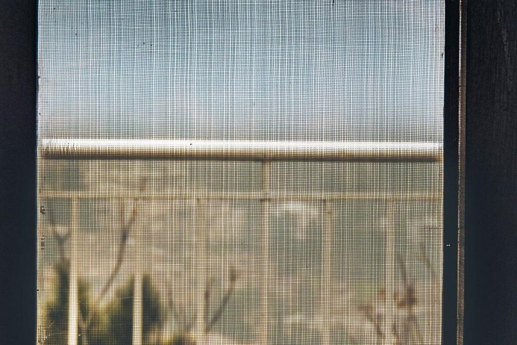 Window with mosquito screen net in autumn, European countryside, no people