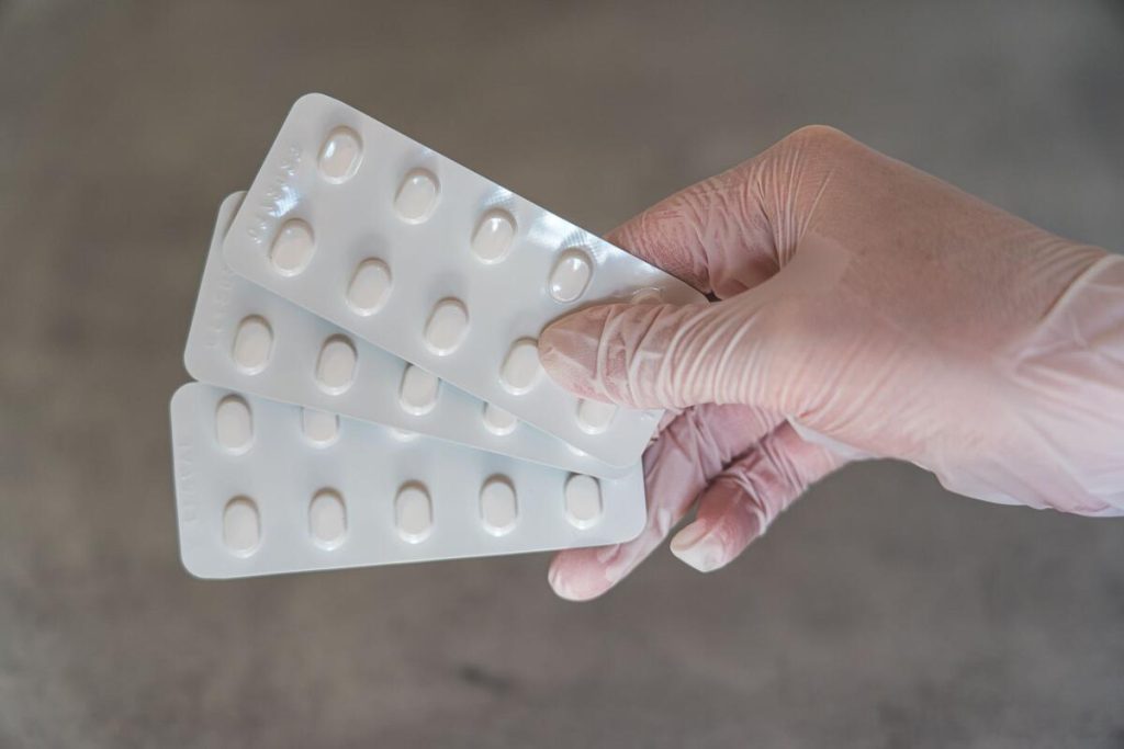 doctor hand holding tablet blister pack, clinical setting, no faces