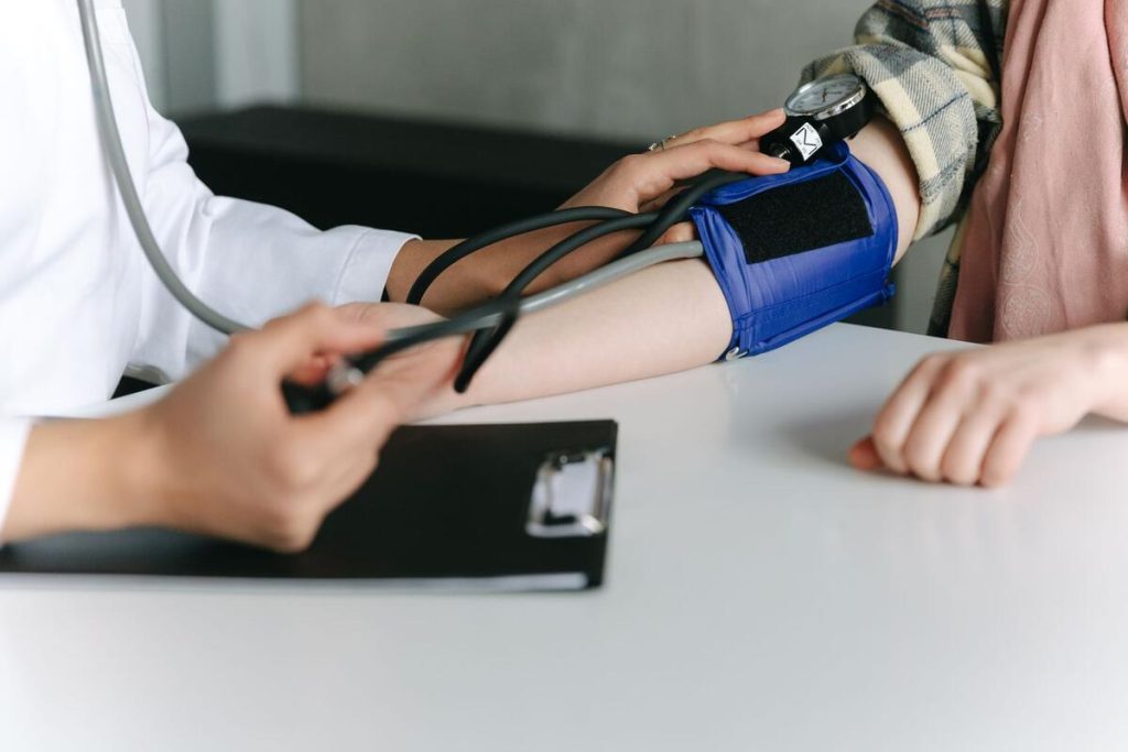 woman having blood pressure checked by a healthcare professional, close up on arm and cuff, no faces visible