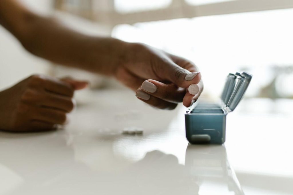 hand holding a daily pill organizer with white tablets