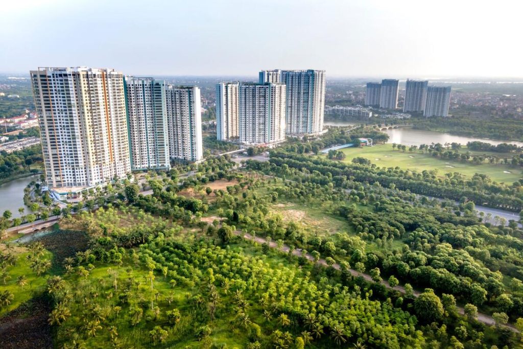 green park with mature trees surrounded by residential apartment buildings, aerial view, no people