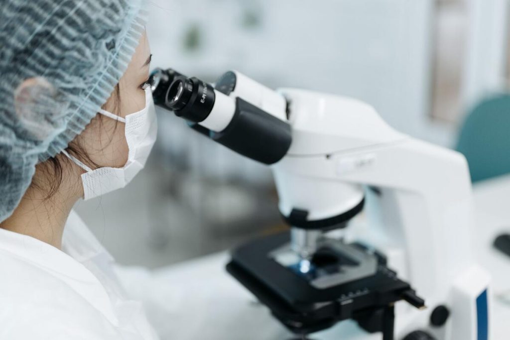 close-up of a medical lab technician analyzing a biopsy sample slide under a microscope, no faces visible