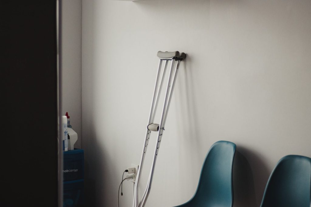 Elderly woman using a walking frame in a hospital corridor after orthopedic surgery, no faces visible