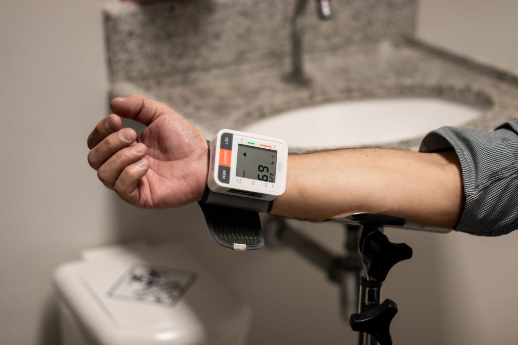 doctor checking blood pressure monitor in clinic, no faces visible