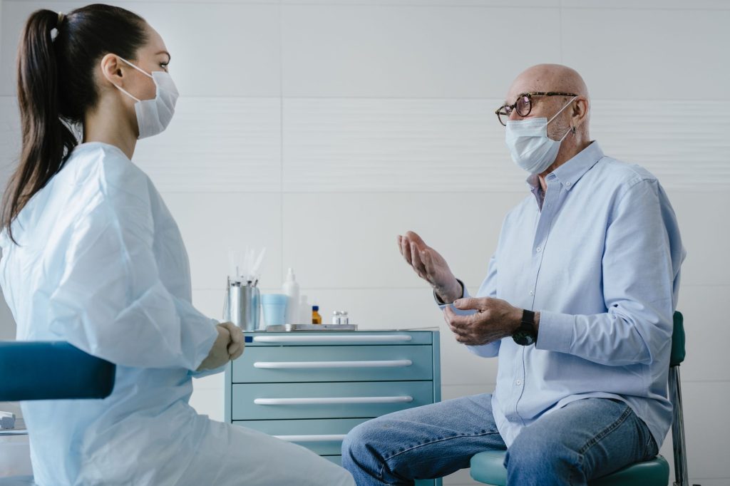 senior man talking with doctor in clinic office, consultation, no visible faces close up