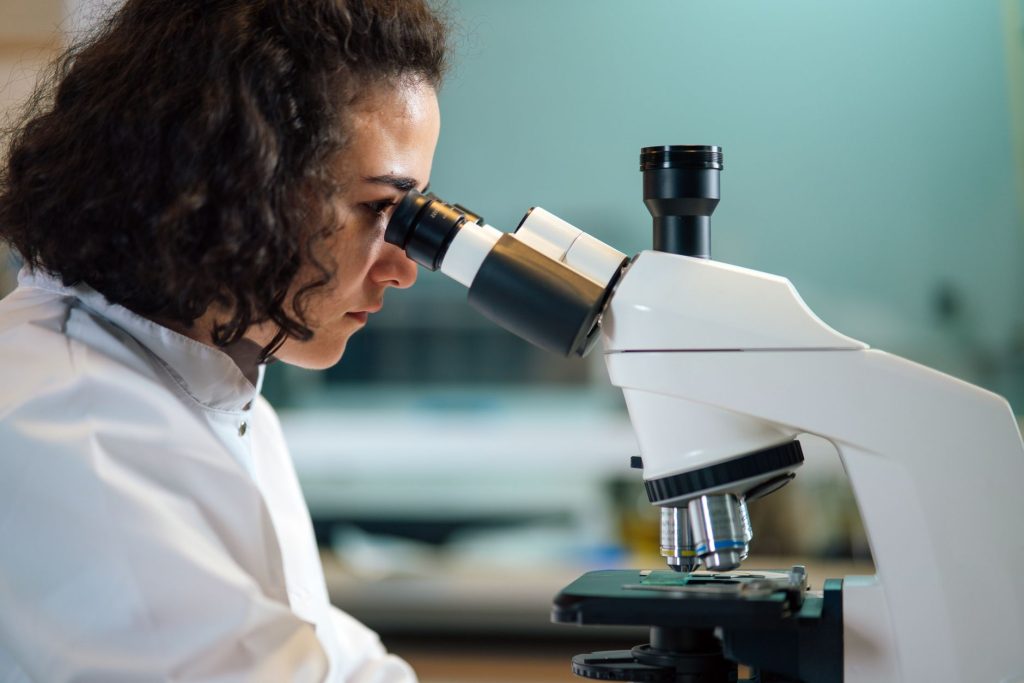 scientist examining tissue sample under microscope in laboratory