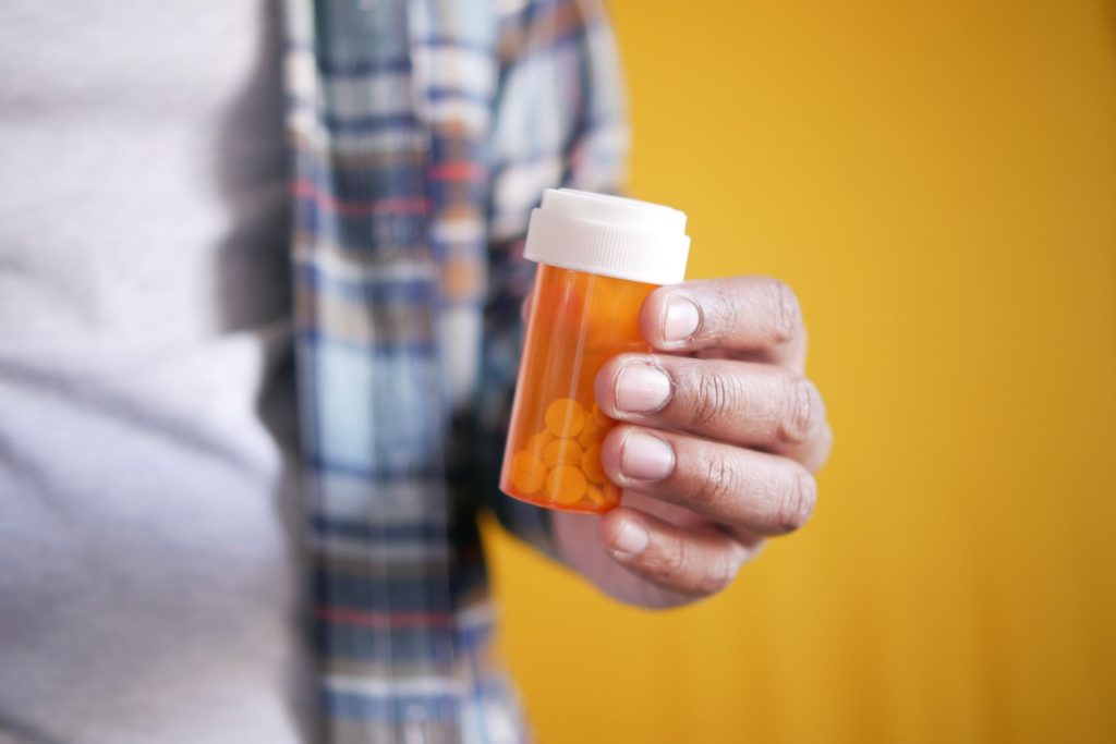 close-up of hands holding a small medication bottle on a kitchen counter, soft morning light, no faces