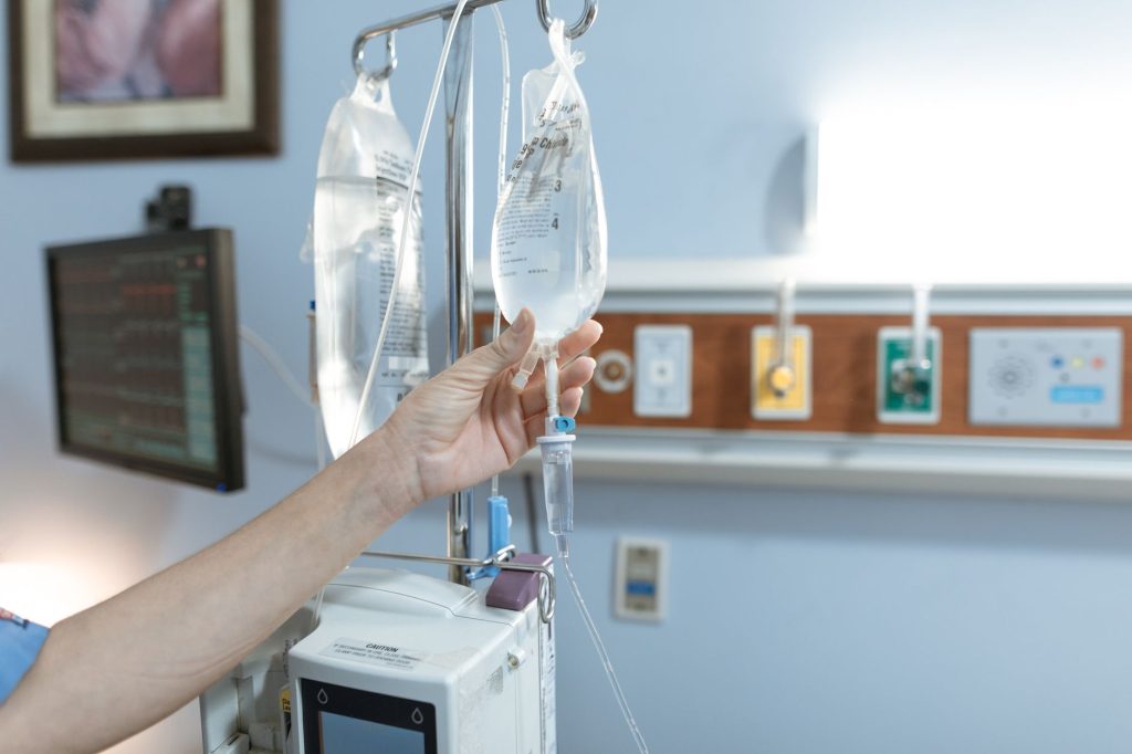 nurse preparing IV infusion stand in hospital corridor, no visible faces