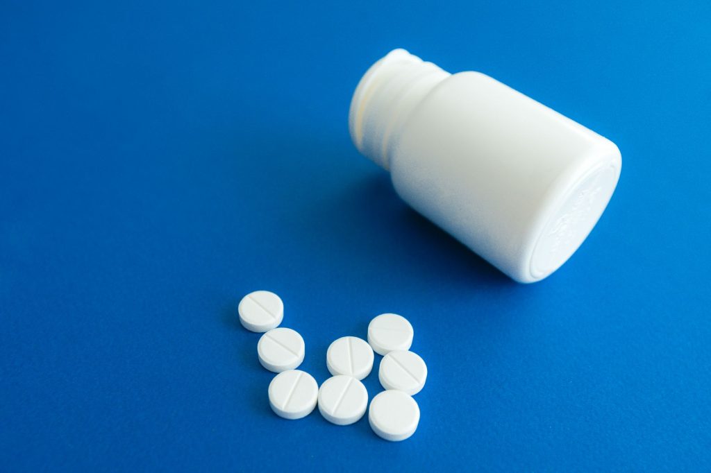 prescription medication bottle and white pills on pharmacy counter